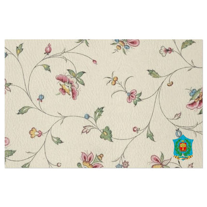 These handmade-to-order FeelGood Breakfast placemats feature a textured white background with a pastel floral pattern. Pink, yellow, and blue flowers are intertwined by green vines, with a vibrant emblem at the bottom right corner. Ideal as designer breakfast placemats.