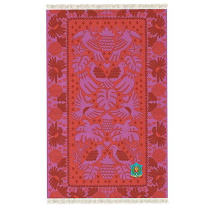 This handmade Rug boasts a vibrant red and purple textile with intricate woven designs of birds, hearts, and leaves. Its symmetrical pattern features stylized elements on a detailed backdrop, complemented by fringed edges for an artisanal touch.