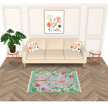 A minimalist living room features a beige sofa with floral cushions on a vibrant handmade rug. Two wooden side tables and a potted plant add charm, while a floral painting on the paneled wall above enhances elegance.