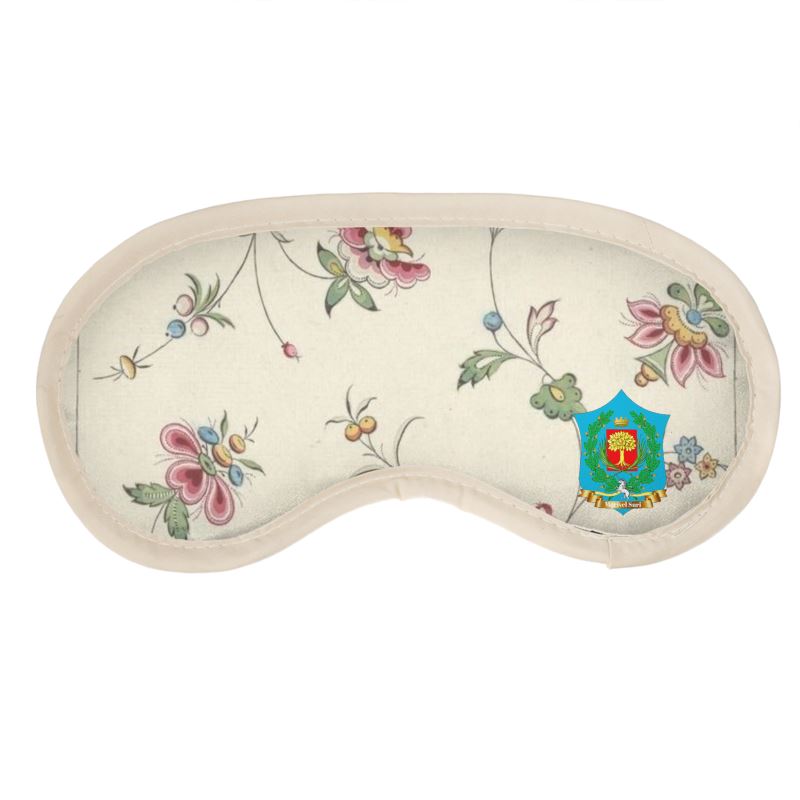 The FeelGood Sleep eye mask showcases a floral pattern of vibrant flowers and green vines, framed by a cream border. Made from soft satin with quilted cushioning for added comfort, it features an ornate colorful emblem on the right side.