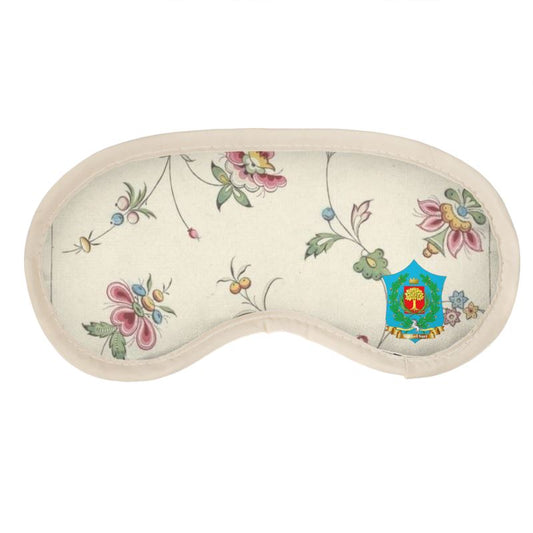 The FeelGood Sleep eye mask showcases a floral pattern of vibrant flowers and green vines, framed by a cream border. Made from soft satin with quilted cushioning for added comfort, it features an ornate colorful emblem on the right side.