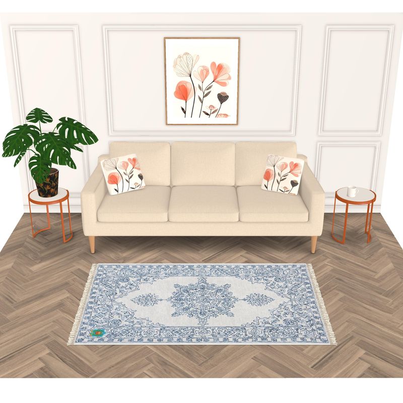 A stylish living room features a beige sofa with floral cushions, matching side tables, and a light blue and white patterned rug with an anti-slip base on chevron wood flooring. The cohesive space is enhanced by potted plants and framed floral artwork.